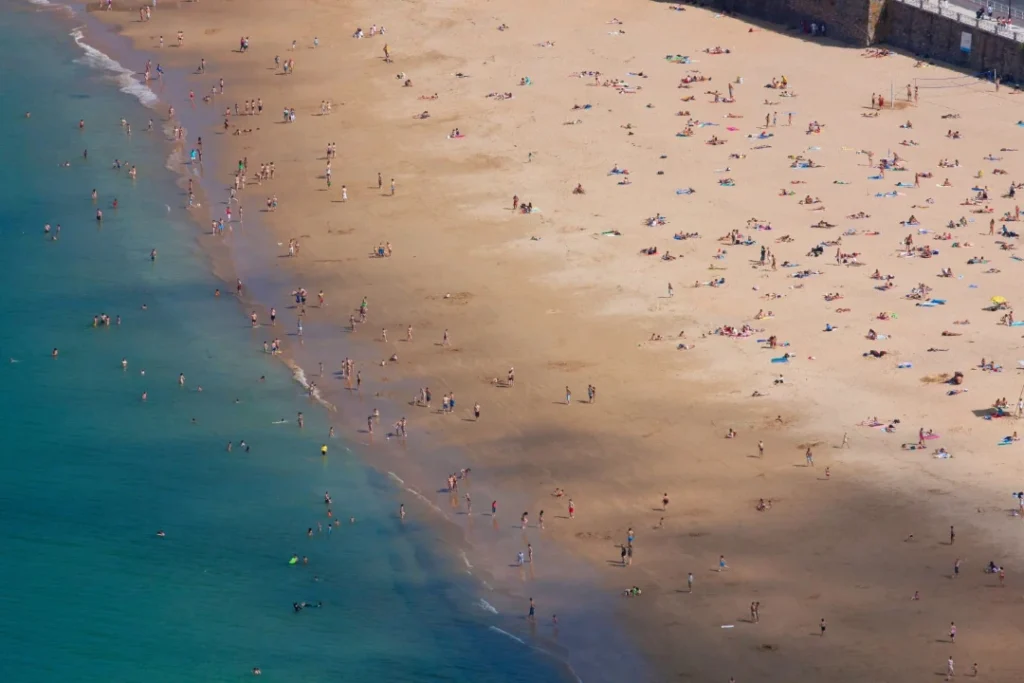 A distant, high-angle view of a crowded beach in northern Spain.