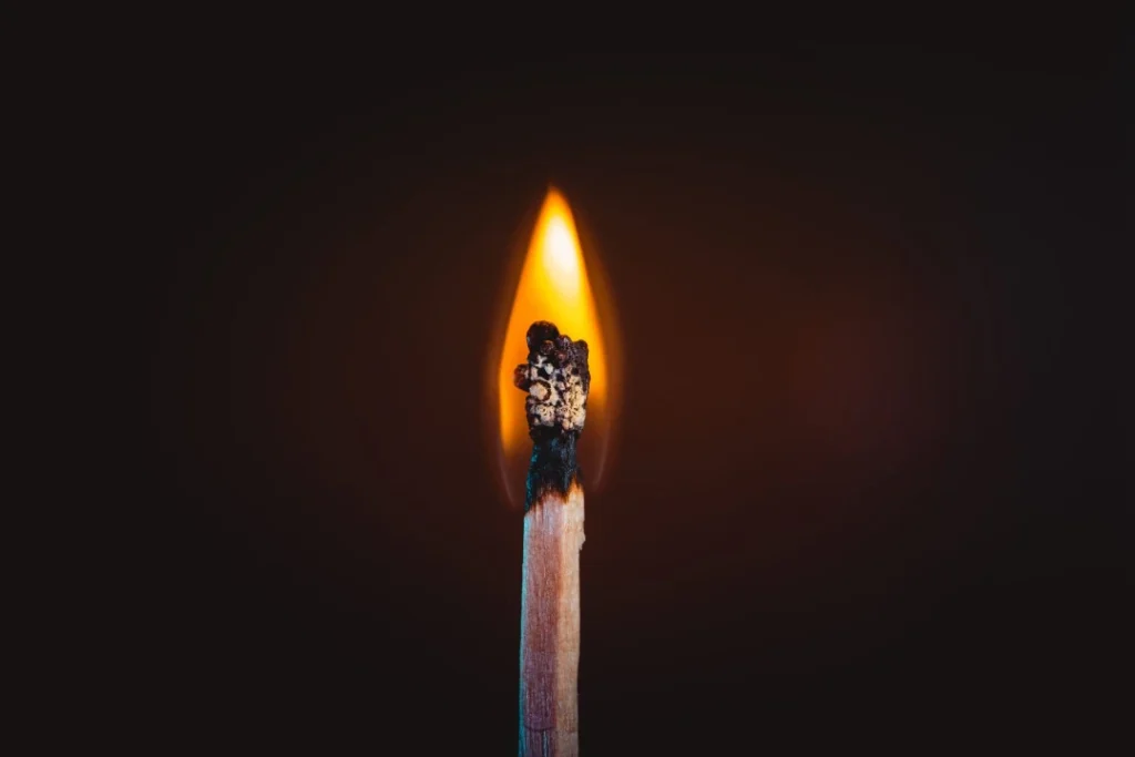 Close-up of a burning match on a black background.